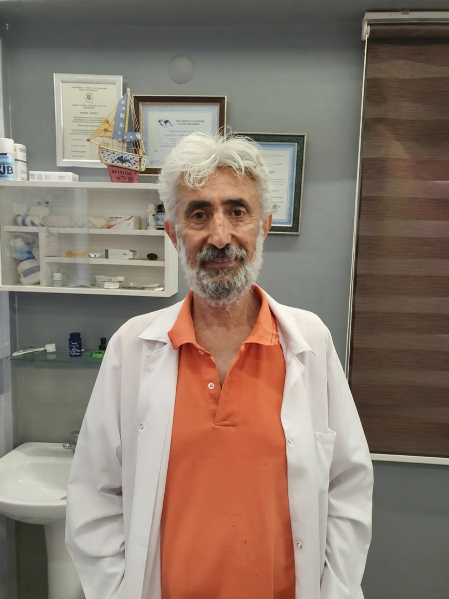 Yavuz Dinler in his clinic, in a white coat and orange polo shirt, certificates on the wall behind him